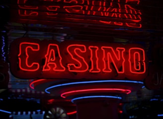 Neon lights display the word 'CASINO' in bright red, standing out against a dark background. The vibrant glow reflects a lively and bustling atmosphere.